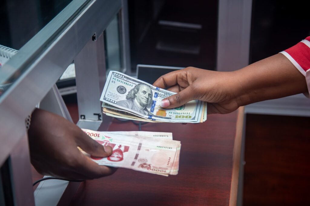 Services Hands exchanging US and local currency at a bank counter, signifying international finance.